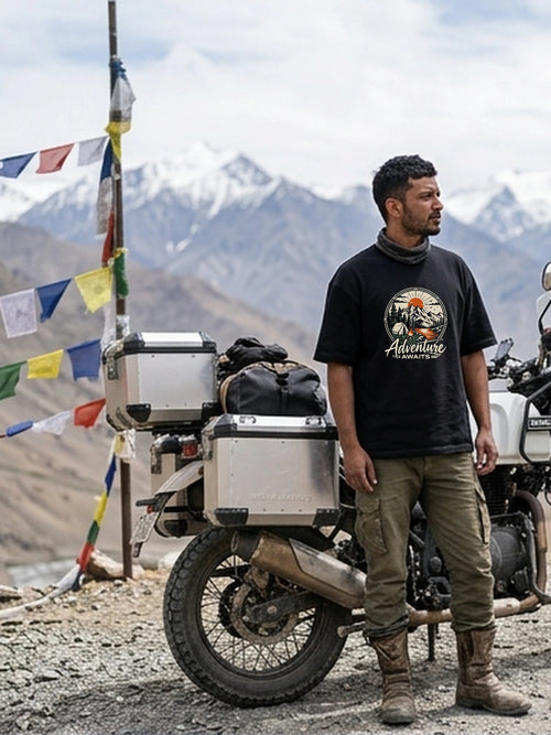 Kabir wearing Adventure Awaits oversized black T-shirt with calibrated 46.1% chest DTG print at high Himalayan mountain pass.