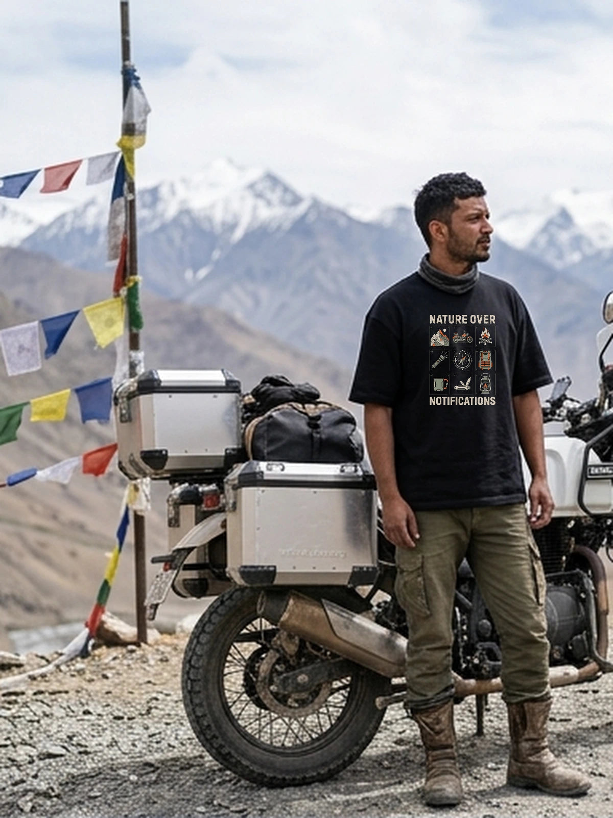 Kabir wearing Nature Over Notifications oversized black T-shirt with calibrated 43.7% chest DTG print at high Himalayan mountain pass.